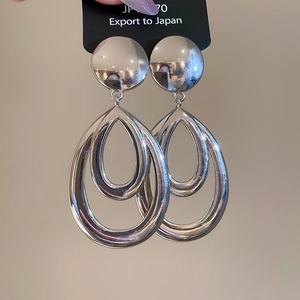 Détail des boucles d'oreilles évidées en forme de goutte d'eau avec une finition argent poli