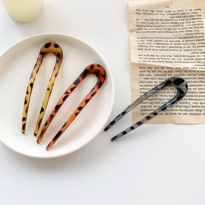 Chic leopard print resin U-shaped hair pins in amber and grey on a decorative plate