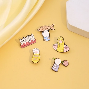 Set of five cute cat paw enamel pins featuring fish and flowers on yellow background