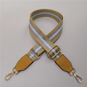 Detail of adjustable wide shoulder strap with yellow stripes and golden metal buckles