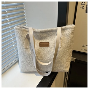 Detail of white plush tote bag showing the brown leather fashion patch and strap