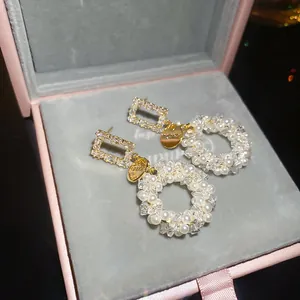 Detail of vintage woven pearl wreath earrings with zircon and gold-plated logo tags