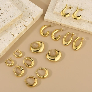 Close-up of assorted gold-plated oval and geometric stainless steel earrings on stone