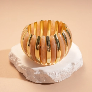Detail of stretch bracelet with gold metal bars and marble resin beads on stone