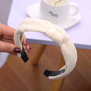 Dettaglio del cerchietto in velluto a coste beige con nodo accanto a una tazza di caffè