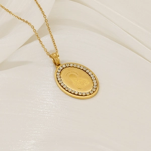 Macro shot of gold Virgin Mary oval pendant with zircon border on white silk fabric