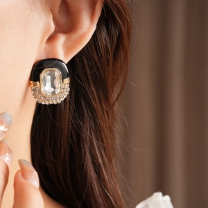 Macro detail of vintage gold oval earring with black enamel and sparkling center crystal
