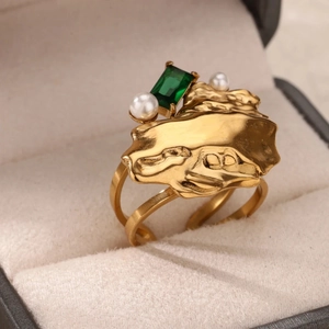 Dettaglio di anello vintage dorato con smeraldo e perle in una scatola di velluto
