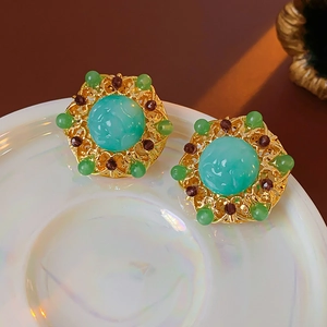 Detail of vintage gold earrings with green stones and intricate hollow metal craftsmanship