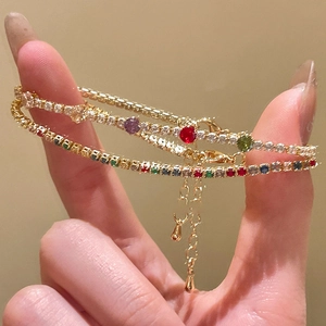 Close-up of gold plated tennis bracelets with colorful zircons and water drop charm