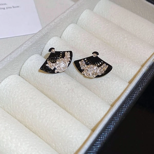 Detail of fan-shaped black earrings with silver relief and rhinestones in jewelry box