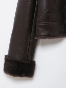 Detailed close-up of dark brown faux leather jacket with plush fur trim on cuffs and hem