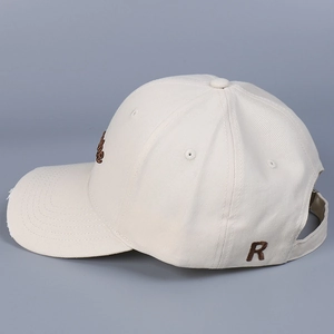 Close-up of cream canvas baseball cap showing brown R letter embroidery and fine stitching