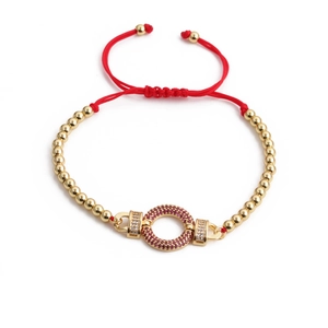 Detail of red woven adjustable bracelet with gold beads and pink zircon pendant