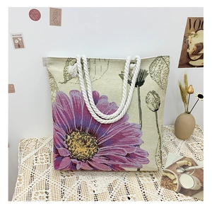 Close-up of beige canvas tote bag with purple dahlia flower print and cotton rope handles
