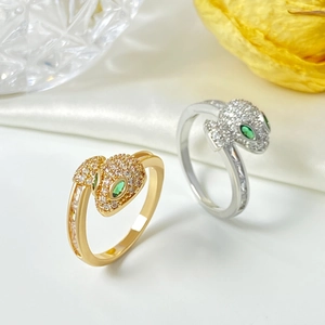 Macro view of micro-paved snake rings with green emerald eyes on white silk fabric
