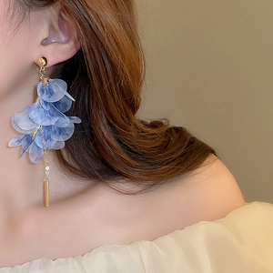 Détail de boucles d'oreilles fleurs en dentelle bleue avec de longs glands élégants