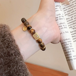 Detailed shot of tiger eye beaded bracelet with gold heart charm and square gemstone