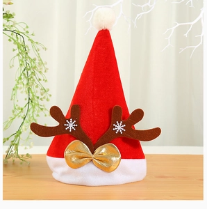 Close-up of velvet Christmas hat with reindeer antlers and golden bow on wood table