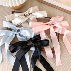 Detailed view of large satin bow hair clips in cream, blue, pink, and black colors