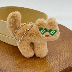 Detailed close-up of a brown plush cat charm with green heart sunglasses and silver chain