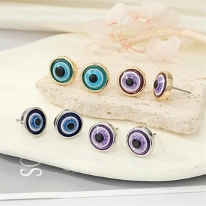 Macro shot of colorful resin evil eye stud earrings on elegant white textured stones
