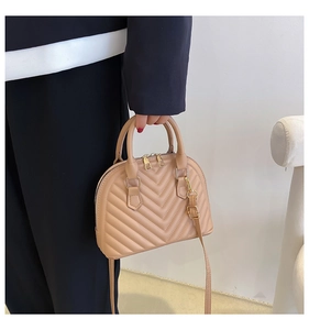 Detail showing beige shell bag with V-shaped quilting and golden metal zipper hardware