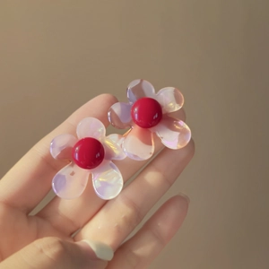 Macro shot of iridescent resin flower earrings with red centers and elegant hook design
