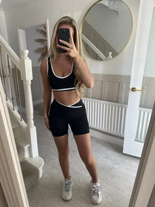 Détail de l'ensemble brassière et short de sport noir avec liseré blanc sur modèle