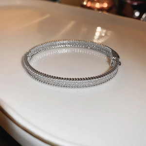 Detailed macro shot of a silver luxury zircon bracelet with circular clasp on a white tray
