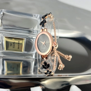 Detailed macro view of the rose gold oval quartz watch with a black floral link bracelet