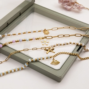 Gros plan détaillé de bracelets dorés 18 carats avec perles colorées et divers pendentifs