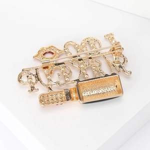 Fashion lipstick brooch in gold metal with red enamel details on a minimalist background