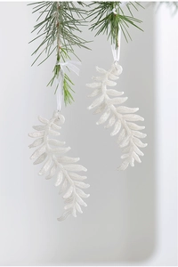 Detail of white glitter acrylic feather ornaments hanging on green pine branch decor