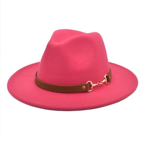 Detail of rose red wool fedora hat featuring a brown leather band and gold horsebit buckle