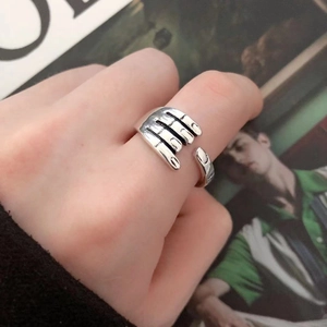 Close-up of a silver hugging hands open ring showing detailed craftsmanship and texture