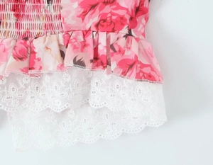 Detail van top met roze bloemenprint, gesmokte textuur en witte geborduurde kant
