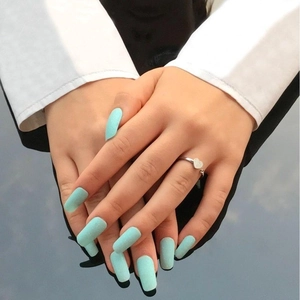 Close-up of matte sky blue long trapezoid press-on nails with heart ring detail
