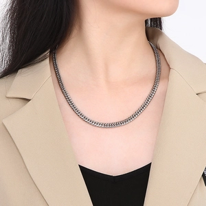 Gros plan d'un collier chaîne gourmette en acier titane argenté porté par un mannequin