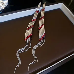 Silver rectangle tassel earrings with vibrant red beads in a luxury display box