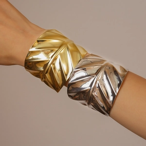 Detailed close-up of wide leaf texture cuff bracelet in polished gold and silver finishes
