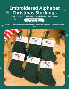 Detail of green knit Christmas stockings with white cuffs and red letter embroidery