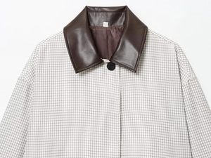 Détail d'une veste courte à carreaux avec col en cuir marron et fermeture boutonnée