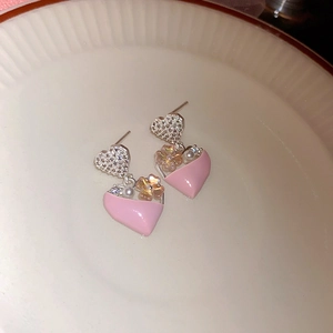 Dettaglio di orecchini a cuore rosa con fiori e perle finte su un piatto di ceramica