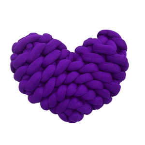 Macro shot of purple hand-knitted heart pillow showing thick yarn texture and detail