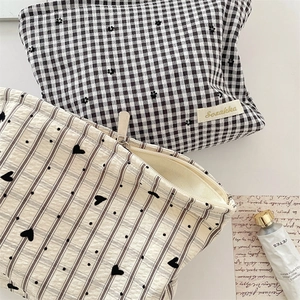 Vue à plat de trousses à maquillage en toile à carreaux et motifs de cœurs