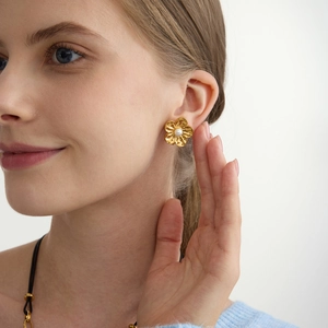 Boucles d'oreilles clips fleurs dorées 18K avec perle portées par un mannequin