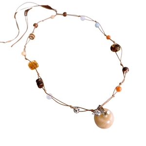 Ethnic braided tiger eye stone apple pendant necklace with ceramic beads on white backdrop