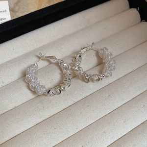 Macro detail of silver woven texture hoop earrings lying on a beige velvet jewelry box