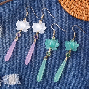 Detail of flower earrings with translucent teardrop pendants on a blue denim backdrop
